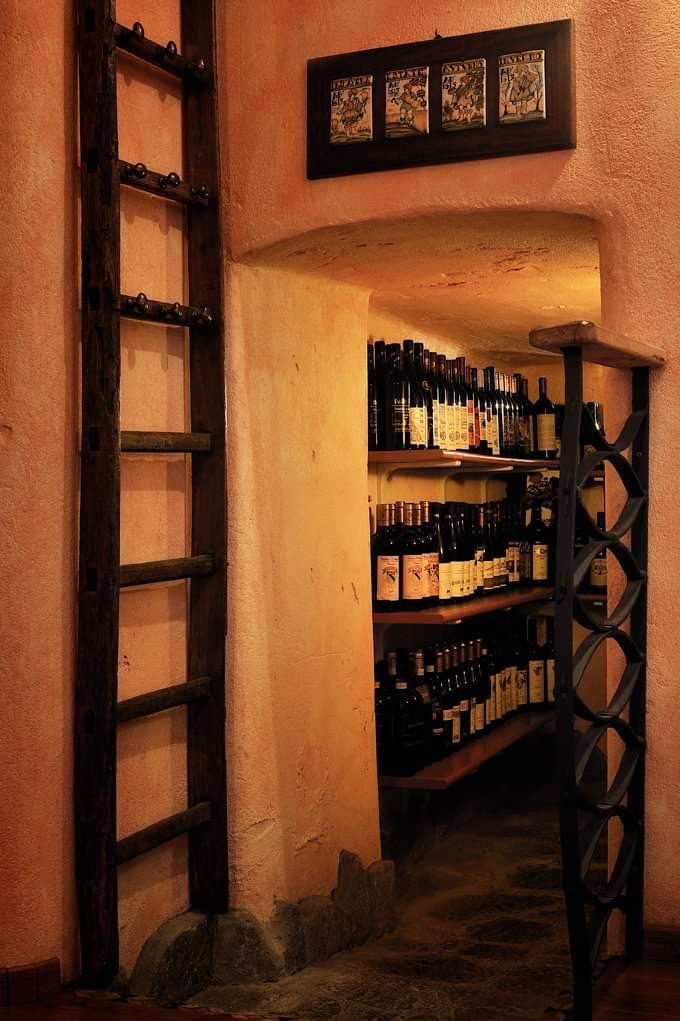 The cellar at Osteria da Nando: bottles on the shelves beneath the stone vault