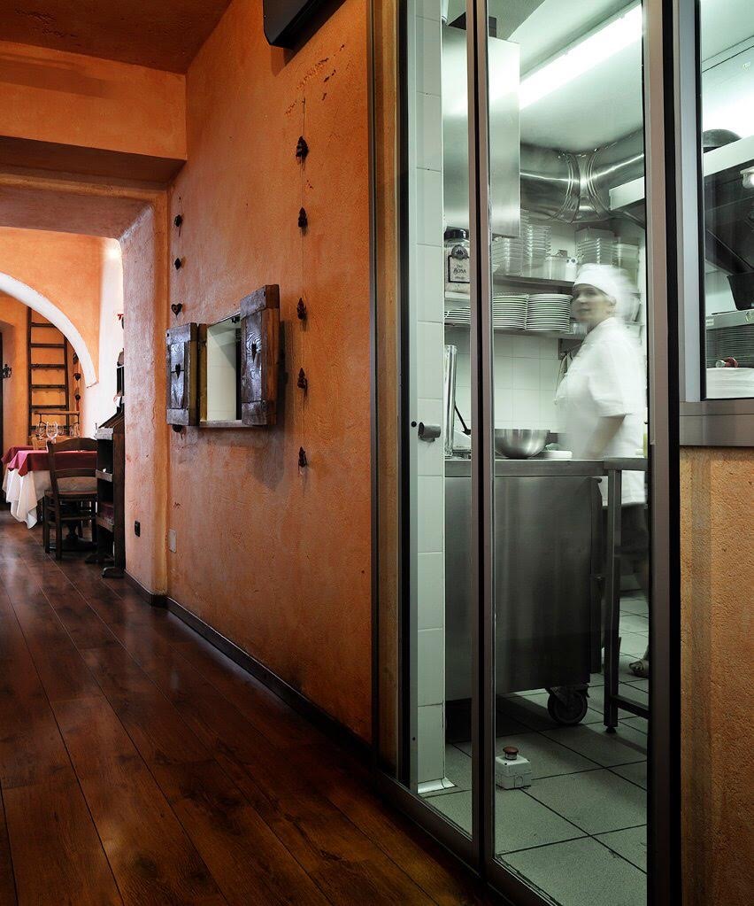 The kitchen at Osteria da Nando seen from the corridor, behind the glass
