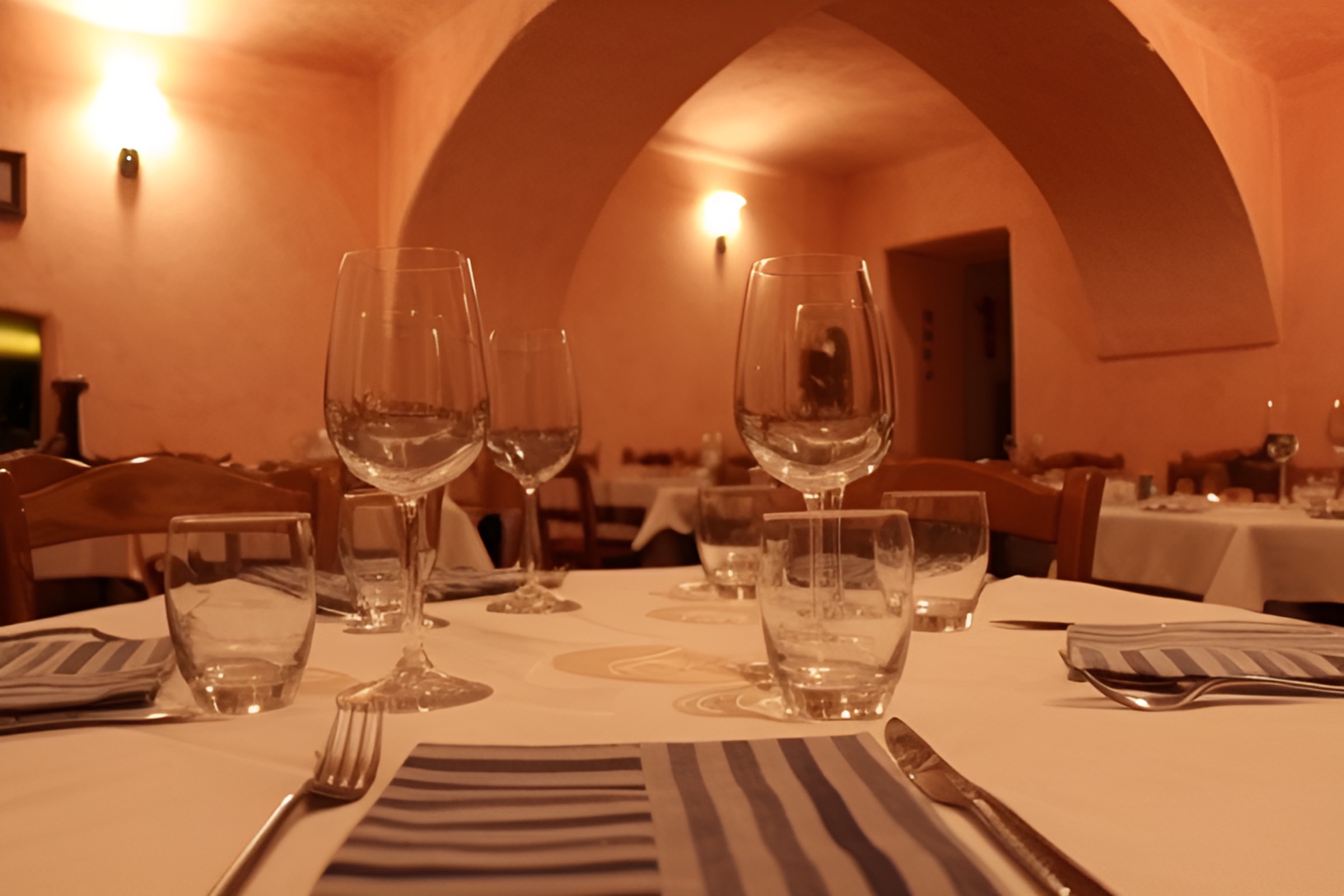 Wine glasses and set tables in the Osteria da Nando dining room