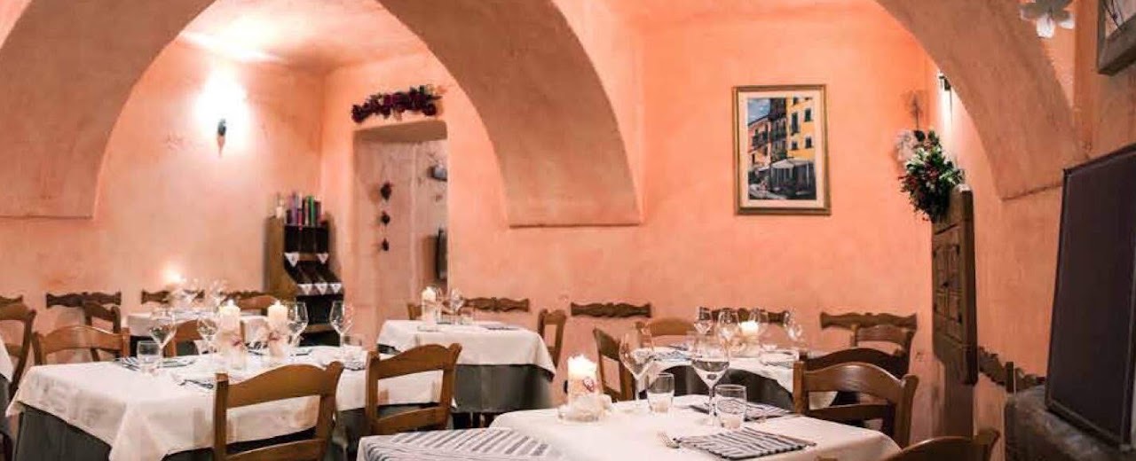 Interior of Osteria da Nando, an intimate dining room in warm pink and brown tones